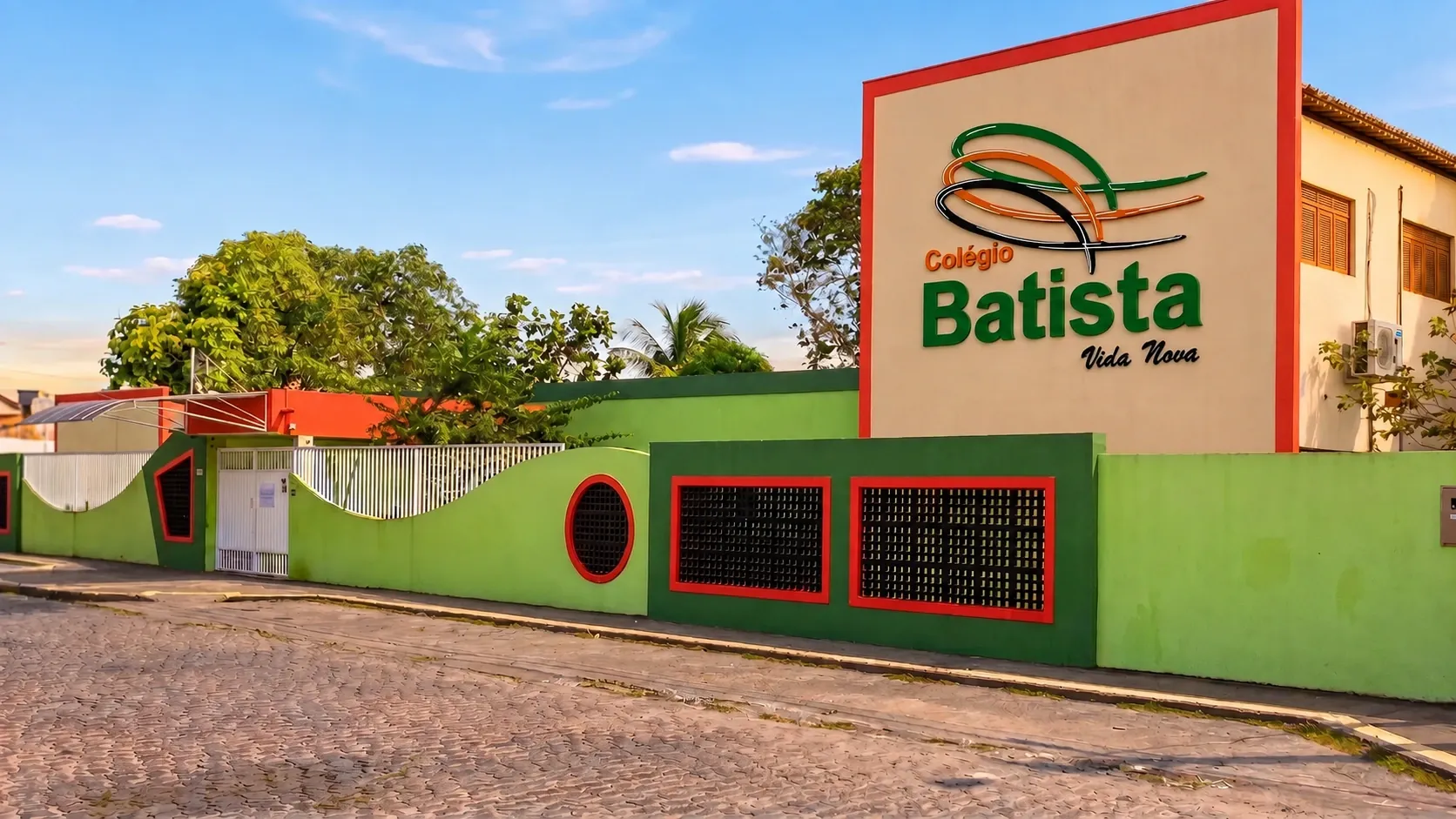 Fachada do Colégio Batista Vida Nova, com o letreiro da escola sobre o muro verde
